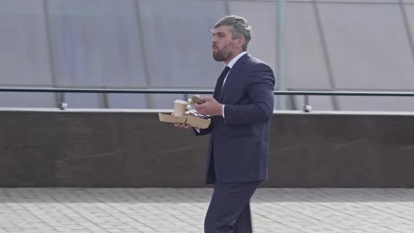 Business man eating fast food on foot