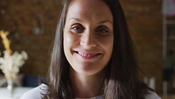 Portrait of smiling caucasian female business owner touching hair and looking at camera alt