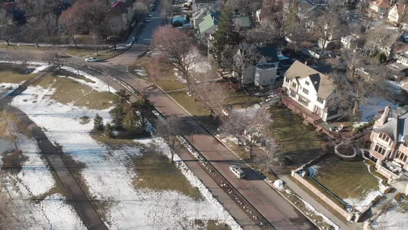 Aerial footage of suburbs in Minneapolis, cars going on a road by the lake shore alt