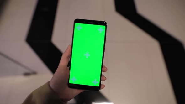 POV, Female Hand Holding Smartphone Green Screen in a Mall