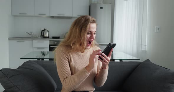 Funny Young Woman Customer Celebrating Winning Bid or Getting Ecommerce Shopping Offer on Smartphone alt