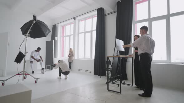 Professional Photo Shooting of Afroamerican Footballer in Studio Backstage Shot with Team alt