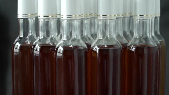 Side View of Glass Bottles with Alcoholic Drink Rotate on Conveyor