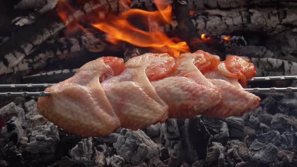 Closeup of Raw Chicken Wings Pierced with the Skewers and Fryed Above the Fire alt