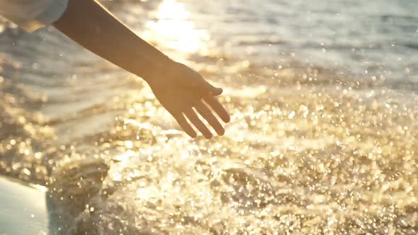 Close Up Woman Hand Gently Touches the Surface of the Water in the Sea