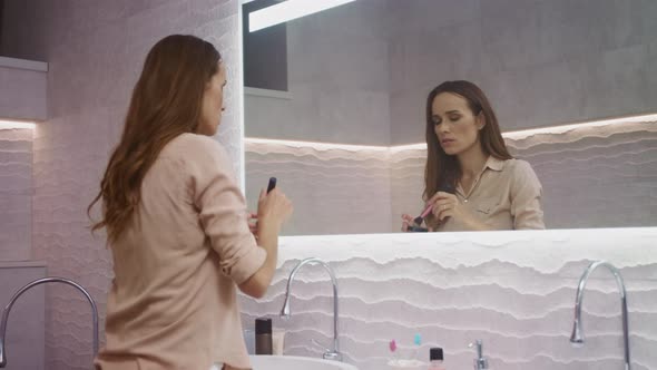 Beauty Woman Doing Makeup in Bathroom. Happy Woman Making Morning Makeup. alt