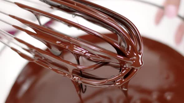 Close Up Delicious Dark Melted Chocolate on Whisk Pouring in Bowl, Slow Motion alt