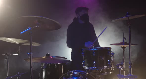 A Man Playing Drums Wearing A Medical Mask
