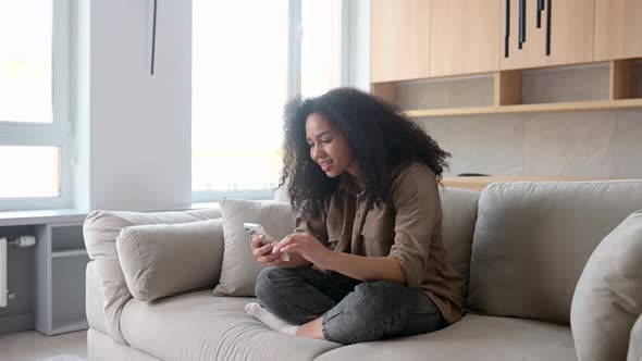 Multiracial Woman Looking at the Camera and Holding Smartphone in Her Hands