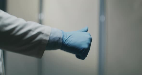 A Male Doctor's Hand with a Medical Glove Points His Thumb Up and Down