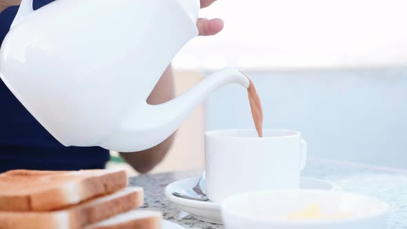 Woman is Pouring a Coffee with Milk  From Teapot to White Cup Closeup