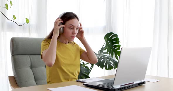 Woman Putting on Headphones While Sitting in Front of a Laptop alt