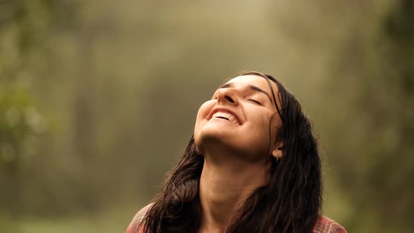 Close-up of a Young Happy Woman with Closed Eyes Enjoying the Warm Summer Rain in the Forest.