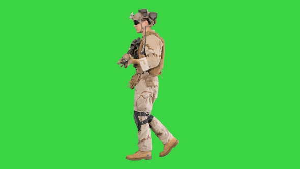 Armed Man in Camouflage with a Gun Walking on a Green Screen, Chroma Key. alt