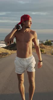 Man In Red Cap Walking Along Empty Road alt