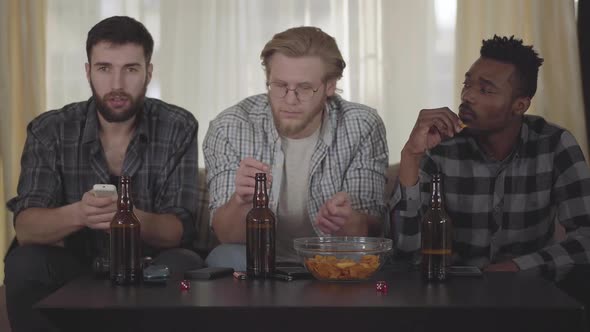 Two Caucasian and One African American Men Resting Together at Home, Having Fun. Beer Bottles alt