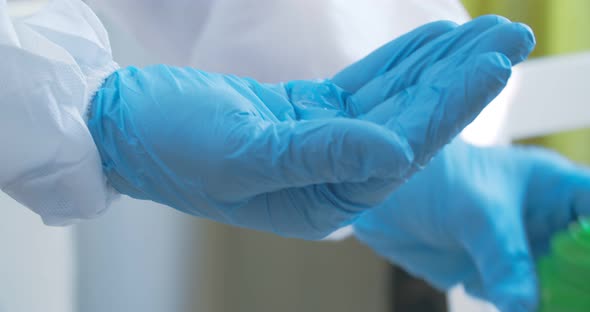 A paramedic in blue rubber gloves treats hands with an antiseptic from the virus