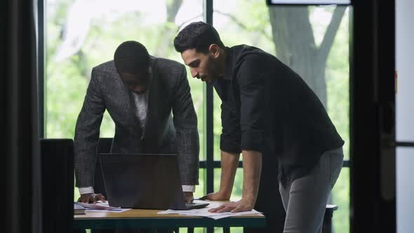 Young Concentrated African American and Middle Eastern Men Discussing Project Strategy in Office alt