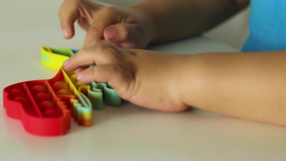 Child plays with rainbow Pop it fidget toy. 