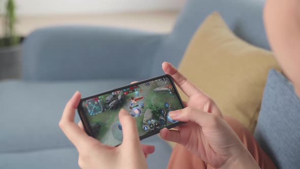 Female Playing Game Online On Smartphone At Home Living Room alt