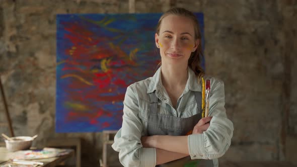Satisfied Female Artist Posing Near New Picture Next to Easel alt