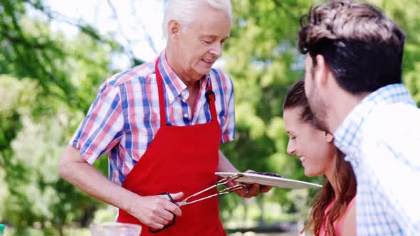 Senior man serving meal to his family alt