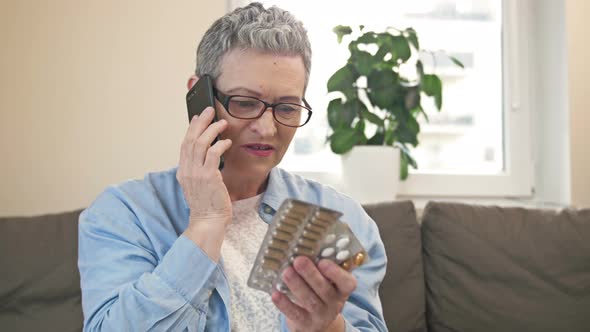 Mature Woman Consults with Someone on the Phone Before Taking the Medicine She Needs