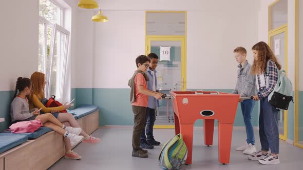 Boy Playing Table Football with Other Children at the Break in School alt