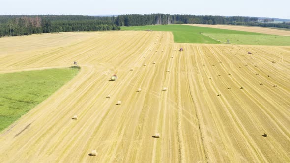 Aerial Drone Shot  a Field with a Tractor and Hay Bales in a Rural Area on a Sunny Day alt