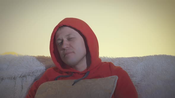 Portrait of a Man in a Hood Watches TV at Night and Switches Channels Negative Emotions alt