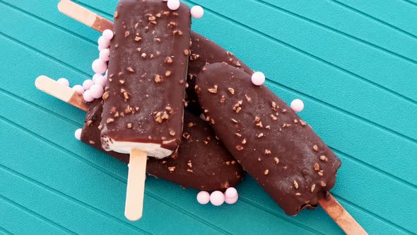 Ice Creams on sticks with pink candies rotating on blue background