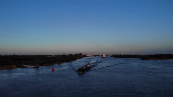 Barge Ship Cruising On Canal River With Speeding Motorboat Overtake During Bluehour In Oude Maas, So alt