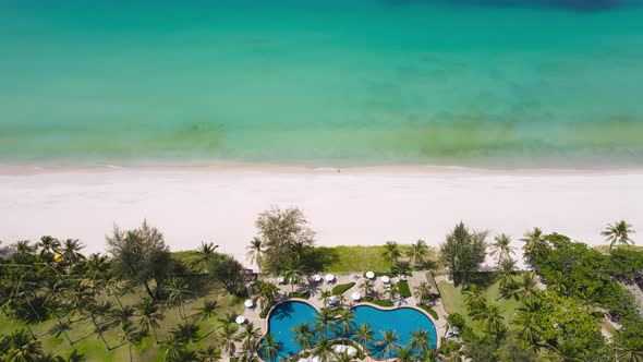 High angle view. The garden and the pool are full of coconut trees on the beach. alt