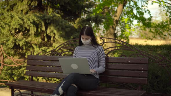 Woman in Medical Protective Mask Freelancer Working with Laptop Outdoor in Park