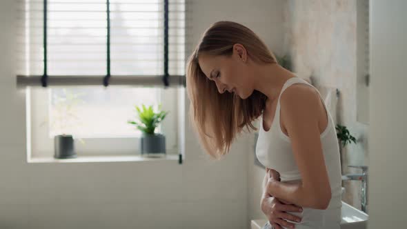 Young caucasian woman standing in the bathroom and feeling pain in the stomach. Shot with RED helium alt
