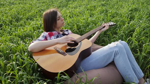 Woman Lies in a Wheat Field Plays Music on Guitar and Sings in Slow Motion at Sunset alt