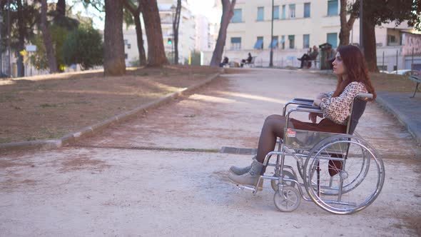 solitude, disability- young woman using wheelchair alone at park looks up alt