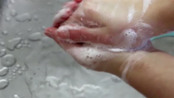 Wash hands with soap close up running water drops