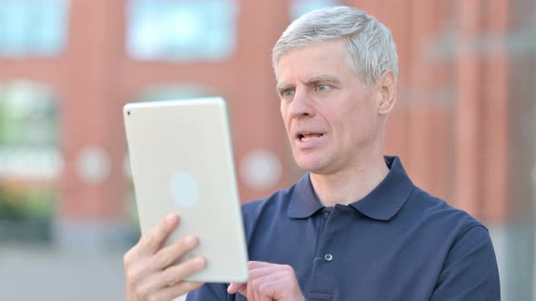 Outdoor Successful Middle Aged Man Celebrating on Tablet alt