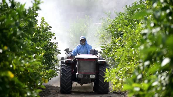 Farm worker spray pesticide driving tractor alt