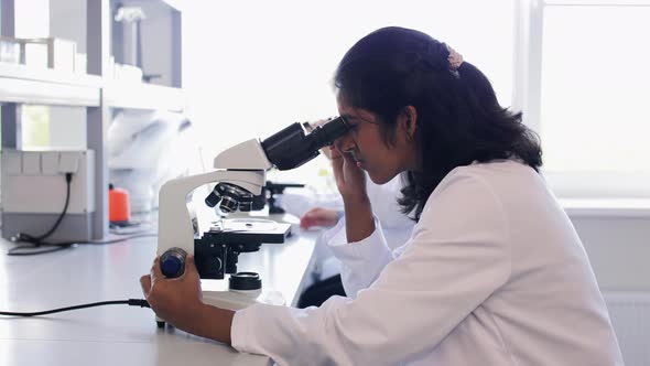 Scientist with Microscope Working in Laboratory