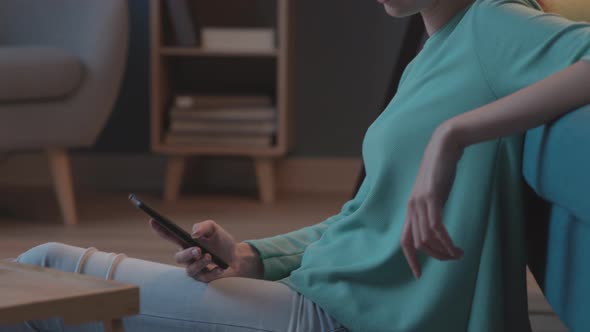 Serene woman chatting with her smartphone at home