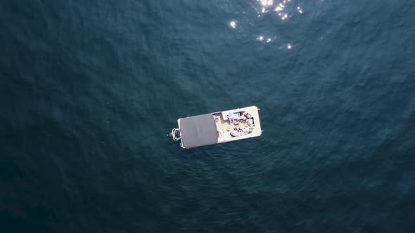 Overhead zoom-out drone shot of a pontoon boat on a sunny day on Payette Lake. This 4K cinematic Ida alt
