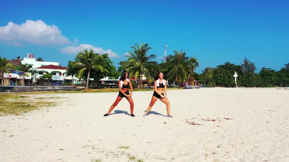 Young happy ladies on vacation enjoying life at the beach on sunny blue and white sand background  alt