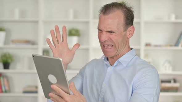 Portrait of Middle Aged Businessman Reacting To Loss on Tablet alt