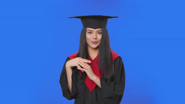 Portrait of Confused Female Student in Graduation Costume Saying Oops Shrugging and Biting Lips alt