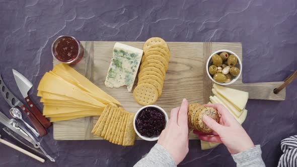 Flat lay. Arranging gourmet cheese, crakers, and fruits on a board for a large cheese board alt