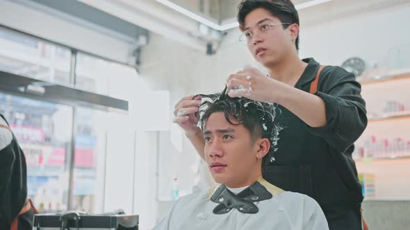Asian hairdresser barber man or hairstylist cut hair of attractive man customer in beauty salon shop alt