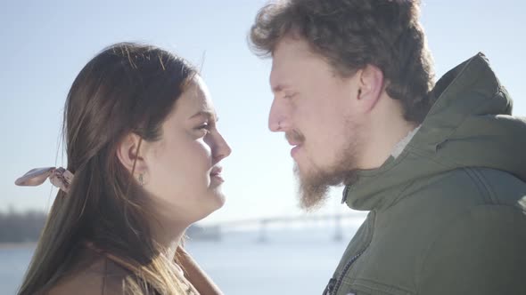 Close-up of Smiling Caucasian Man with Nose Ring and Chubby Brunette Woman Rubbing Noses on River alt