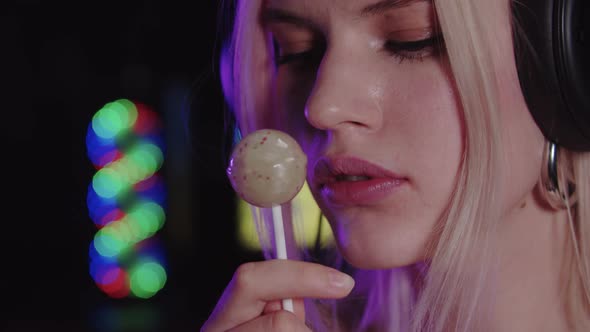 Attractive Blonde Woman Gamer Sucking a Lollipop and Looking in the Camera alt